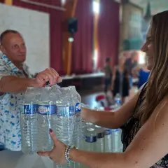 Un homme et une femme échangent des packs d'eau en bouteille, un geste solidaire face au manque d'eau.