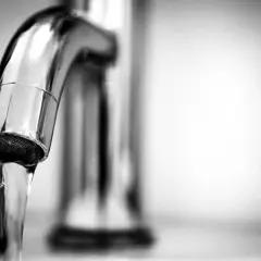 Un robinet chromé laisse couler un filet d'eau pure. L'eau adoucie est prête à boire, offrant une fraîcheur bienvenue.
